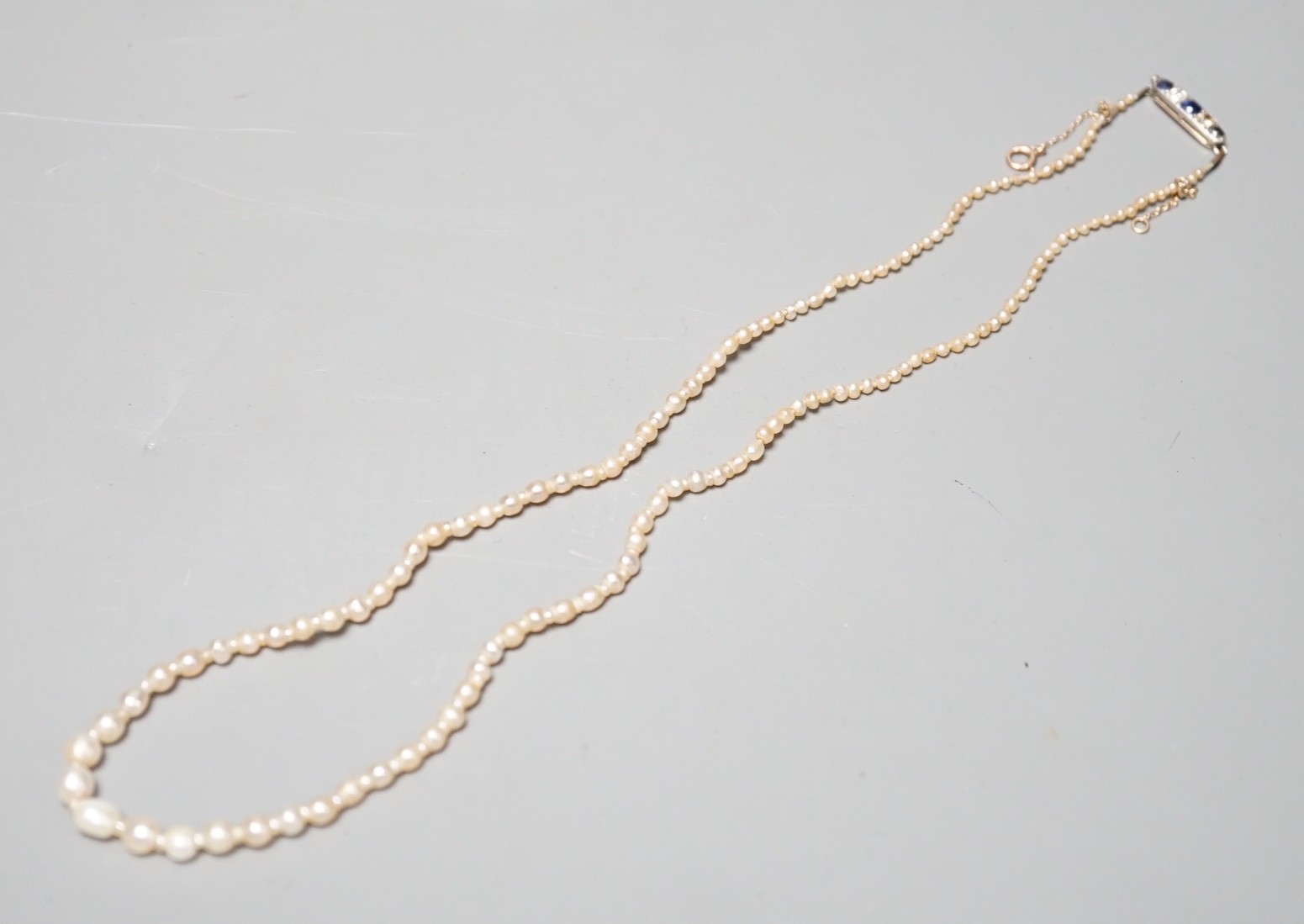 A single strand graduated natural saltwater pearl necklace, with sapphire and diamond set clasp, 44cm, gross weight 7 grams, with accompanying GCS report dated 23/11/2022.